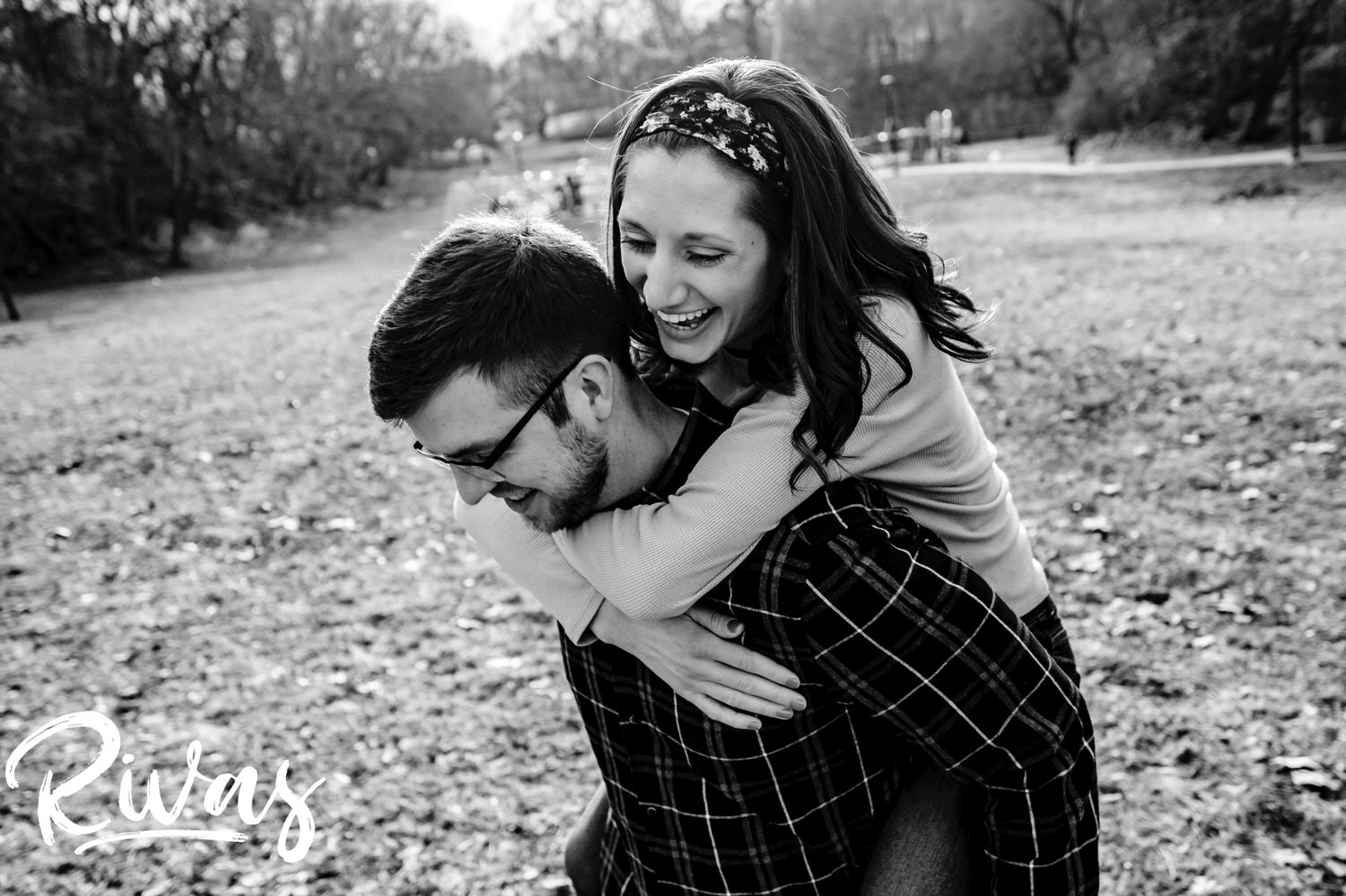 A candid, black and white picture of an engaged couple sharing an embrace and laughing together during their engagement session in Kansas City. 