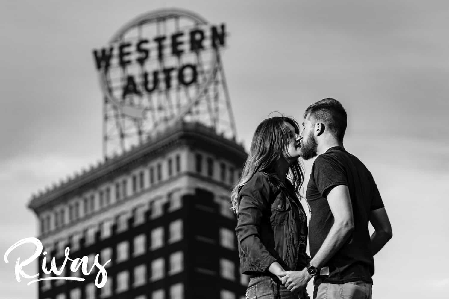 A candid portrait of an engaged couple sharing an embrace in front of the Western Auto Building during their downtown Kansas City engagement session. 