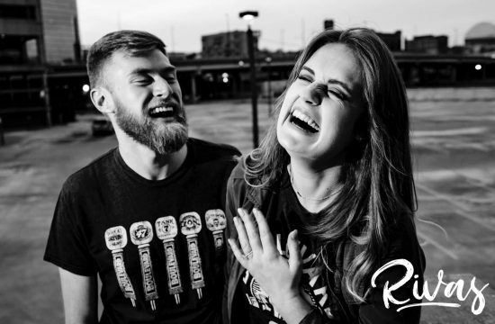 A candid black and white picture of an engaged couple hysterically laughing together during their downtown Kansas City engagement session.