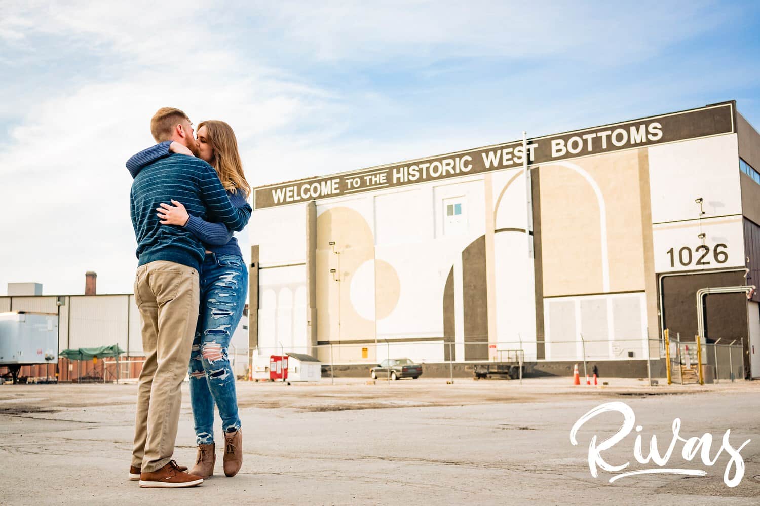 A colorful, candid picture of an engaged couple sharing an embrace and kiss uring their engagement session in Kansas City's West Bottoms. 