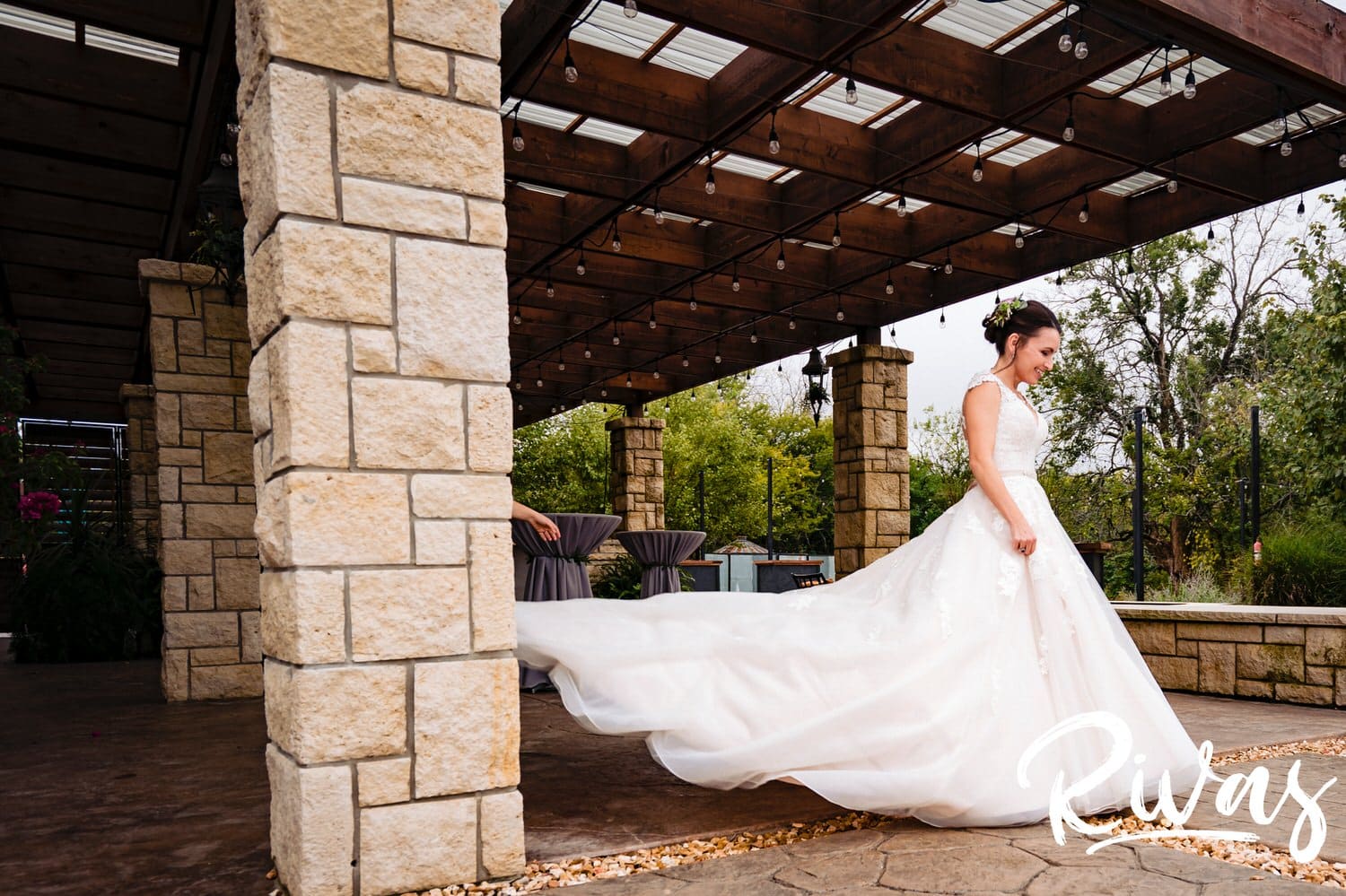 A candid picture of a bride approaching her groom on the patio of The Bowery in Kansas City as her dress flows out behind her. 