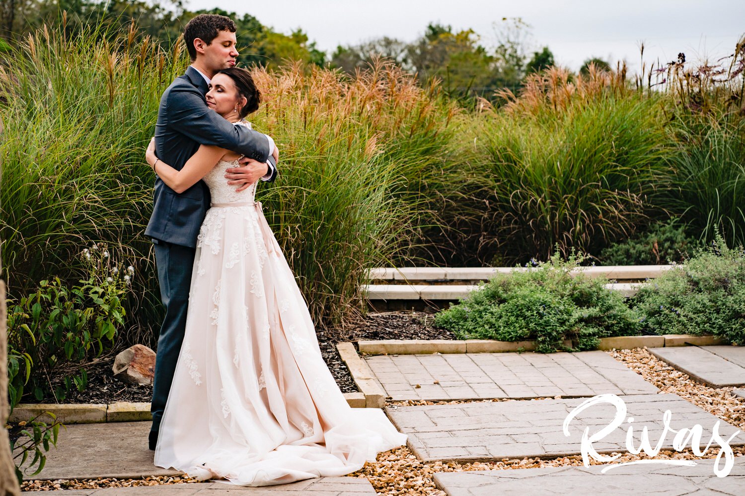A soft, intimate picture taken from a distance of a bride and groom sharing a hug on the terrace at The Bowery in Spring Hill on a rainy wedding day. 