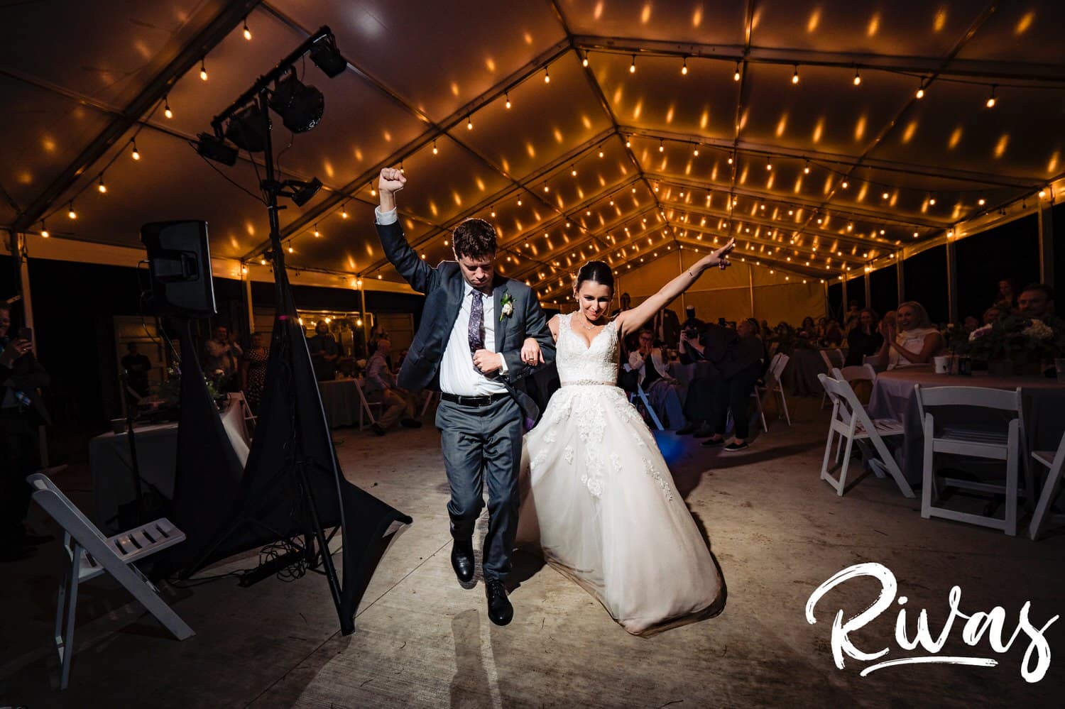 A candid picture of a bride and groom leaving their wedding reception, arms in the air in celebration. 