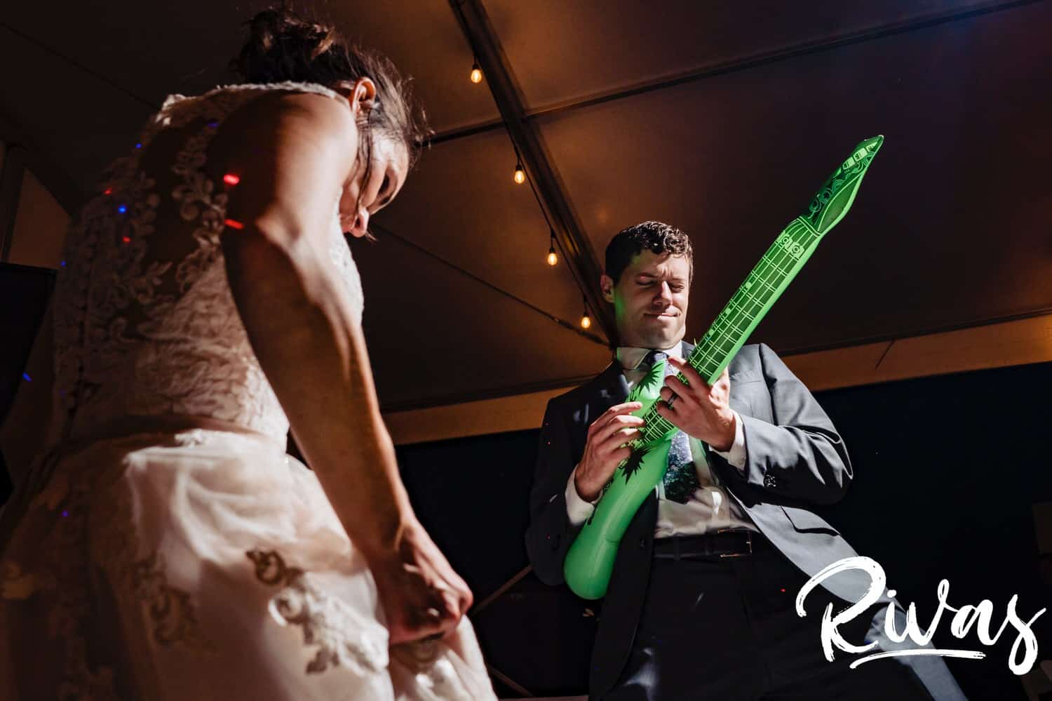 A candid, close-cropped picture of a bride and groom performing an air guitar solo during their first dance at their wedding reception at The Bowery in Kansas City. 