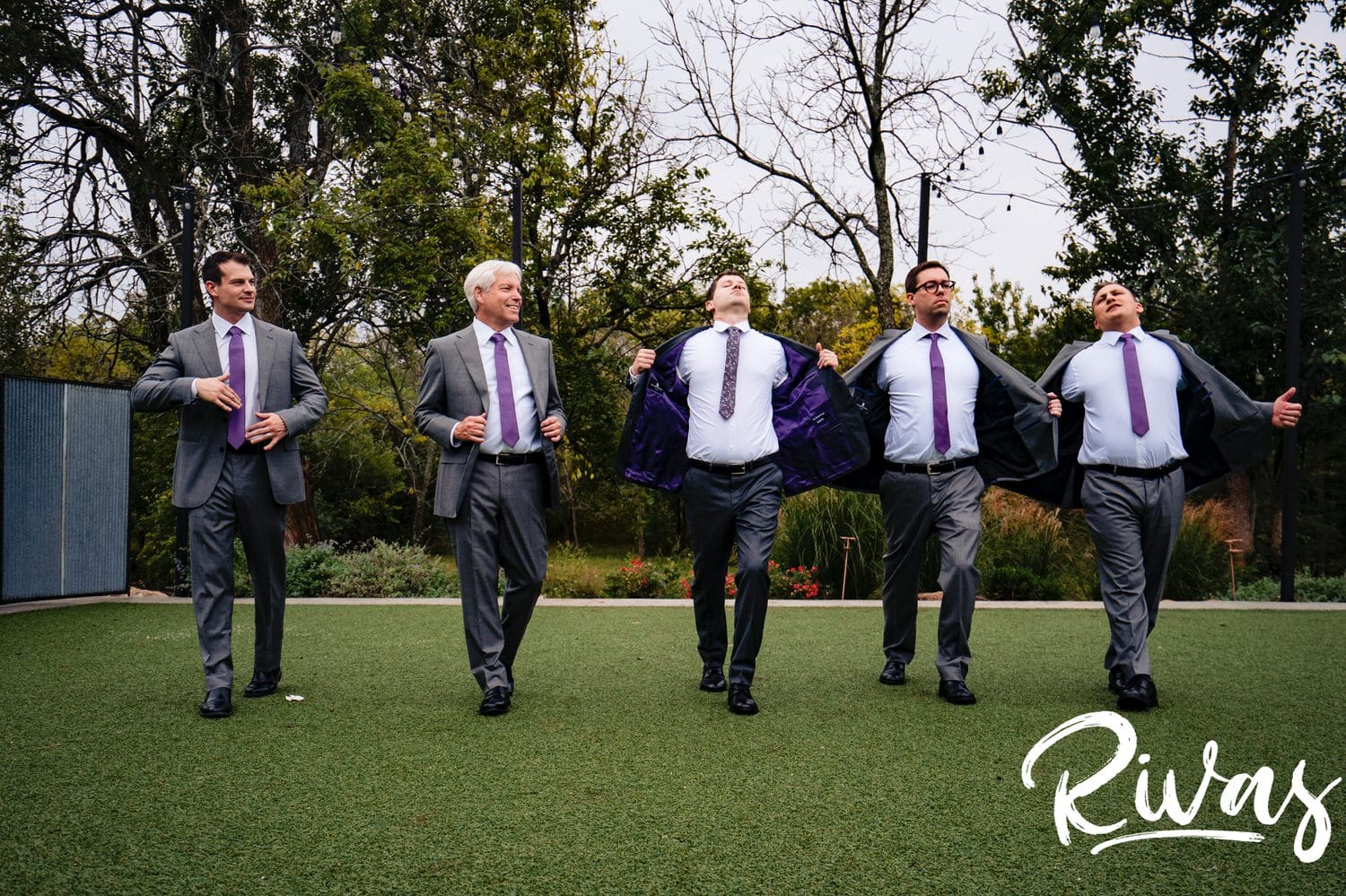 A silly , candid picture of a groom and his groomsmen walking towards the camera as they pull their jackets out to the side on a stormy wedding day at The Bowery. 