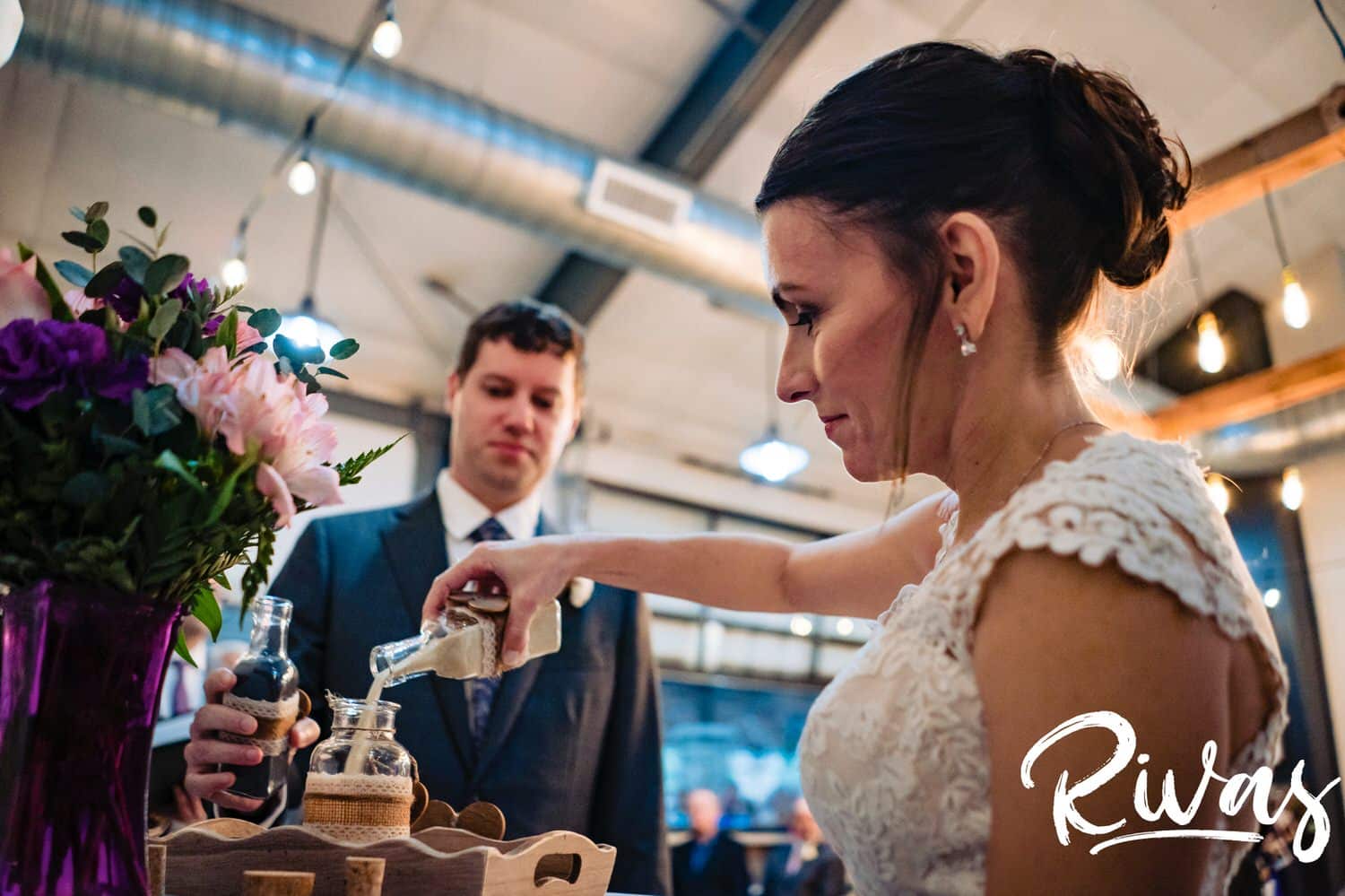 A candid picture of a bride and groom pouring sand into a vase during their unity ceremony at The Bowery. 