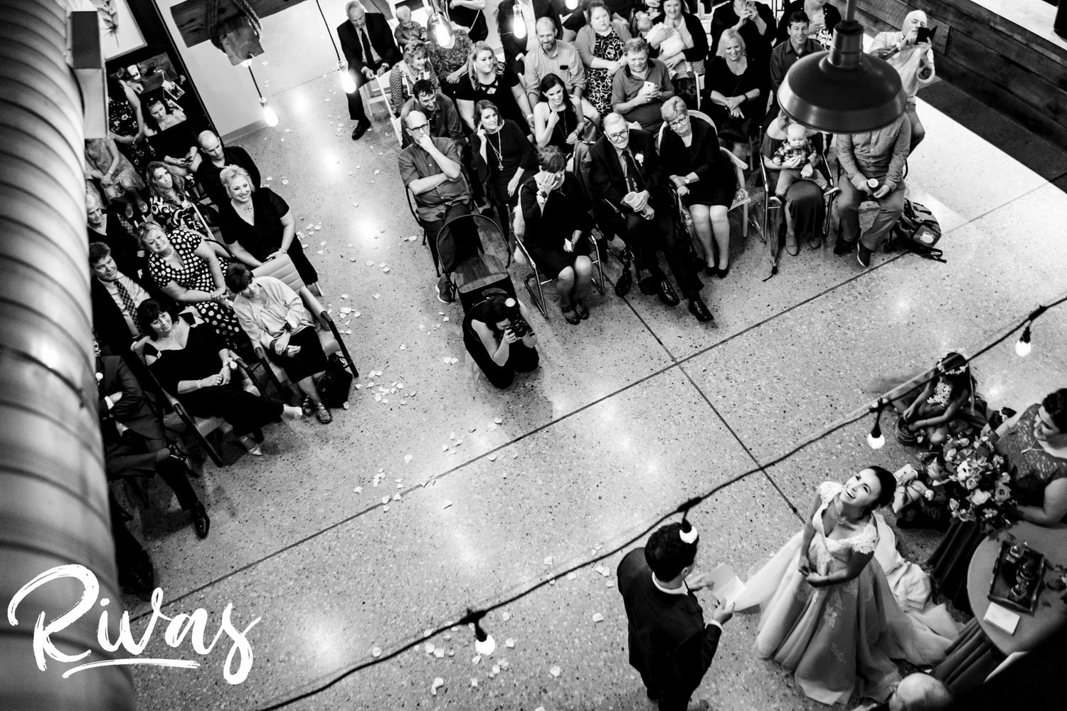 A candid black and white picture taken from above of a bride looking up and laughing during her wedding ceremony at The Bowery on a rainy September afternoon. 