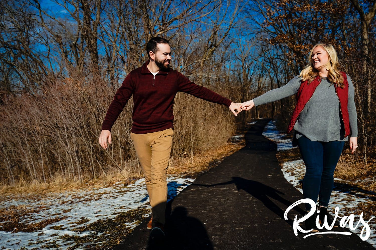 A colorful, candid picture of an engaged couple holding hands walking along a trail during their engagement session. 