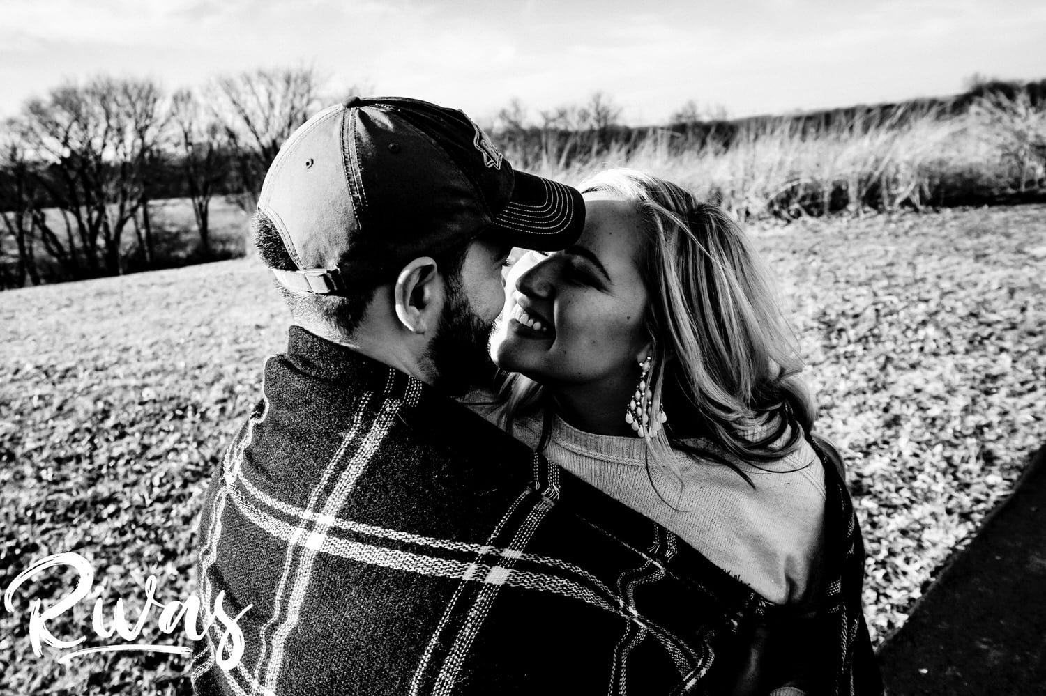 A candid, close-up back and white picture of an engaged couple laughing together during their winter engagement session. 