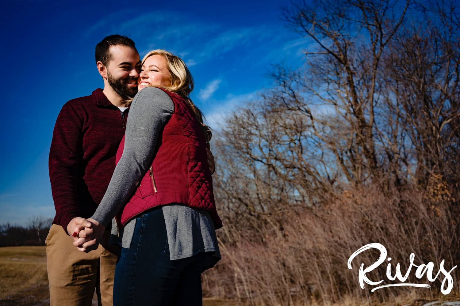 A candid picture of an engaged couple laughing and sharing an embrace together during their sunny winter engagement session in Kansas City. 