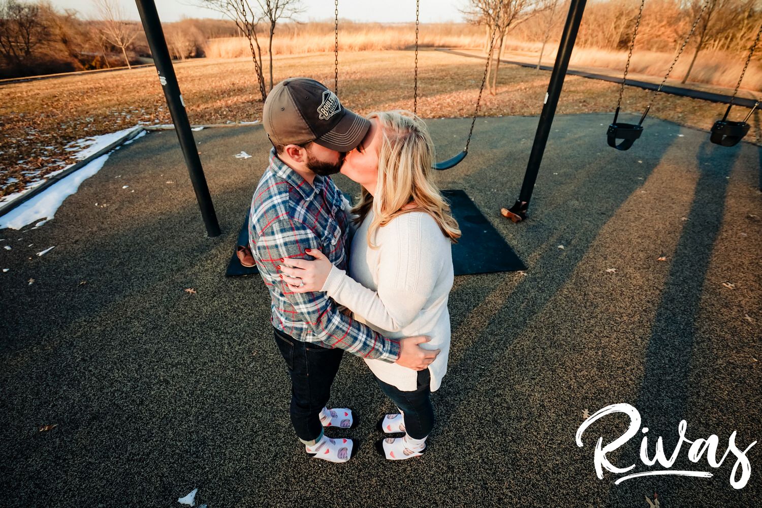 A candid picture of an engaged couple sharing a kiss in their socks at the end of their engagement session in Kansas City. 