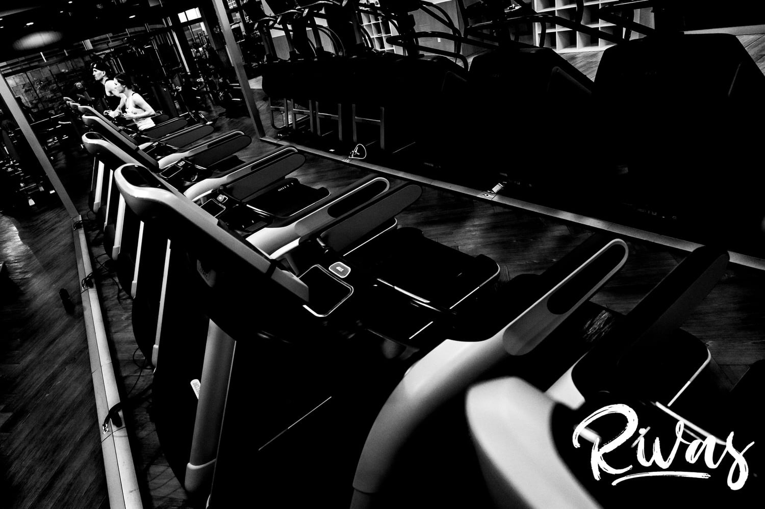 A candid black and white picture of a bride and groom running on treadmills on the morning of their winter wedding at The Station at 28 Event Space. 