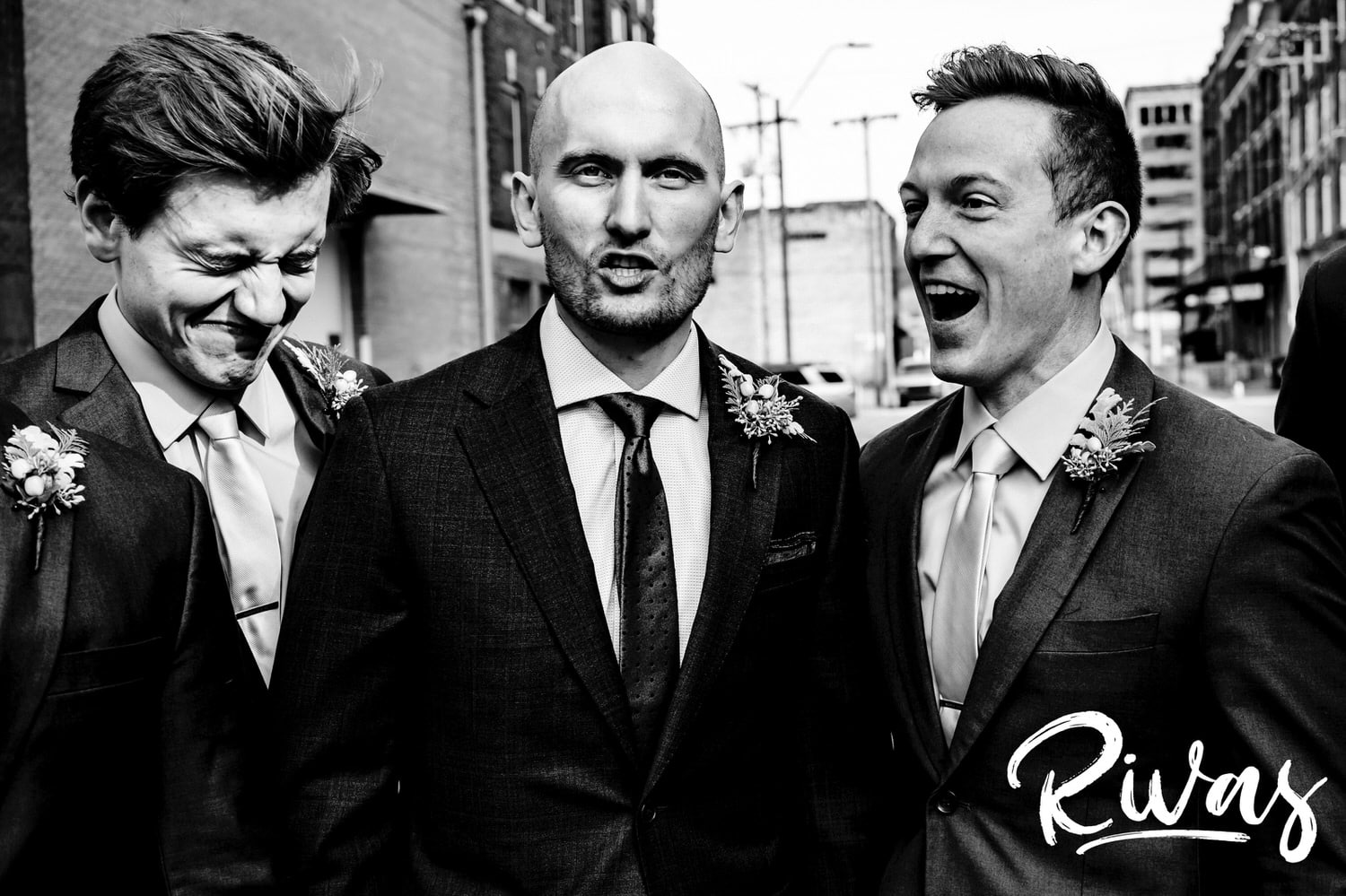 A candid, close up, black and white picture of a groom making a funny face as two of his groomsmen also make funny faces right beside him on a sunny winter wedding day in Kansas City. 