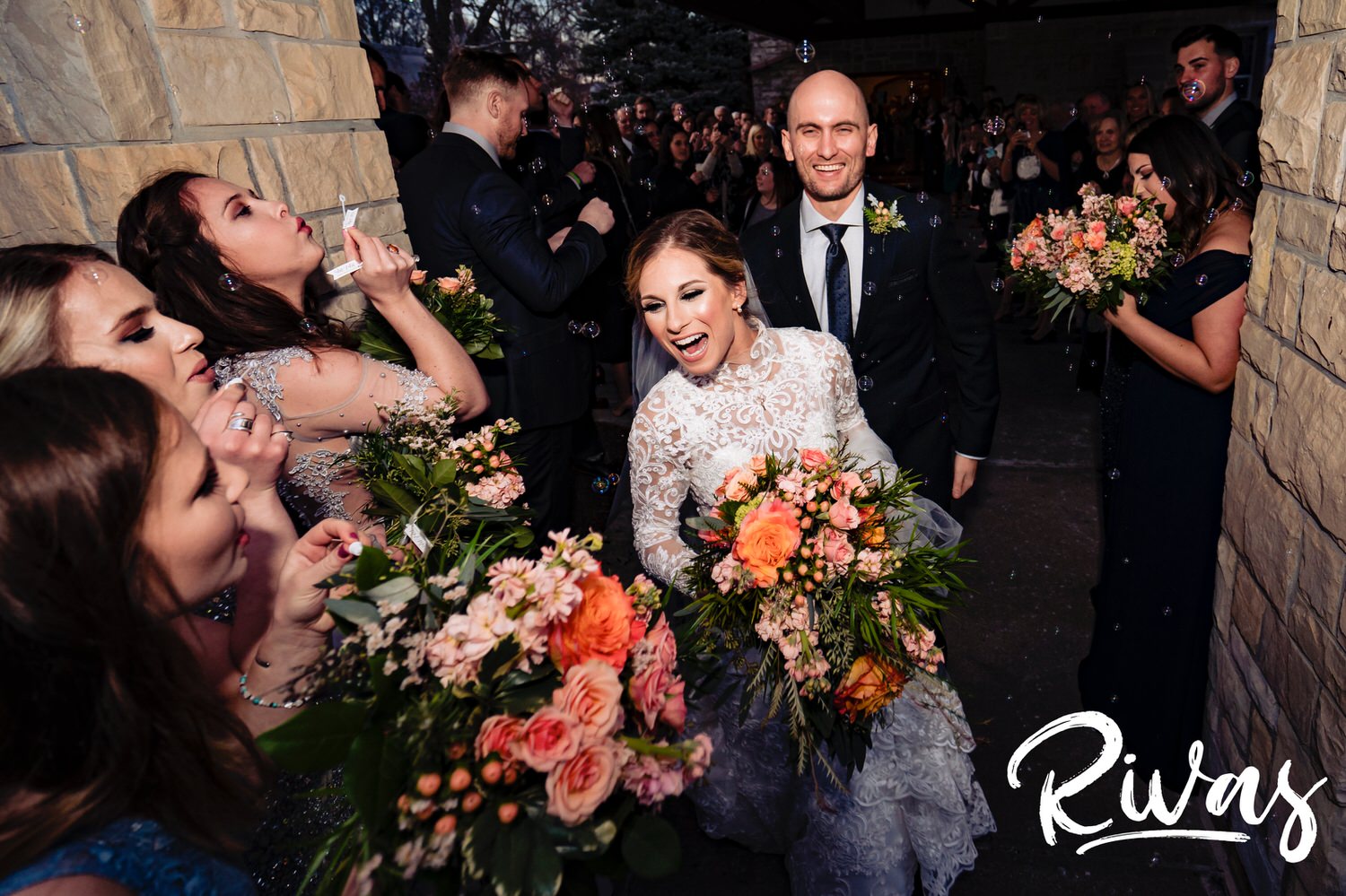 A colorful, candid picture of a bride and groom exiting the church underneath a flurry of bubbles on their winter wedding day in Kansas City. 