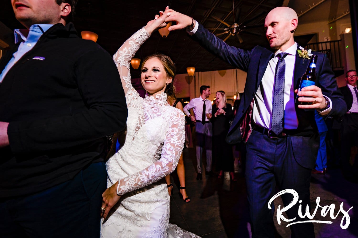 A colorful, candid picture of a groom twirling his bride under his arm during their winter wedding reception at The Station at 28 Event Space. 