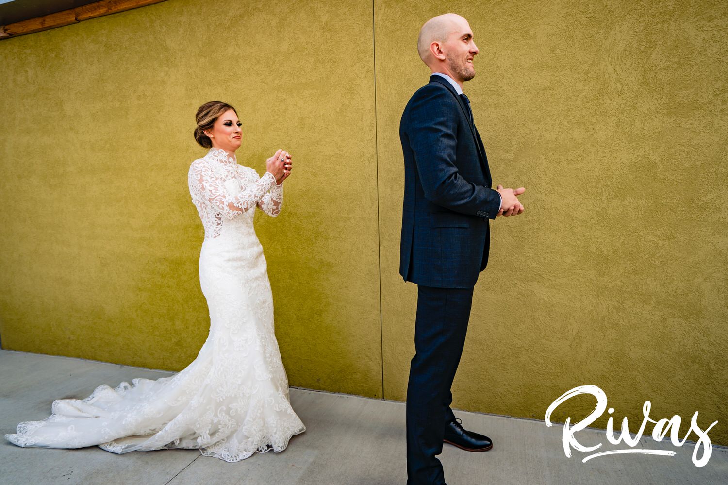 A colorful, candid picture of a bride in a long-sleeve gown walking up behind her groom for their first look on a sunny winter wedding day in Kansas City. 