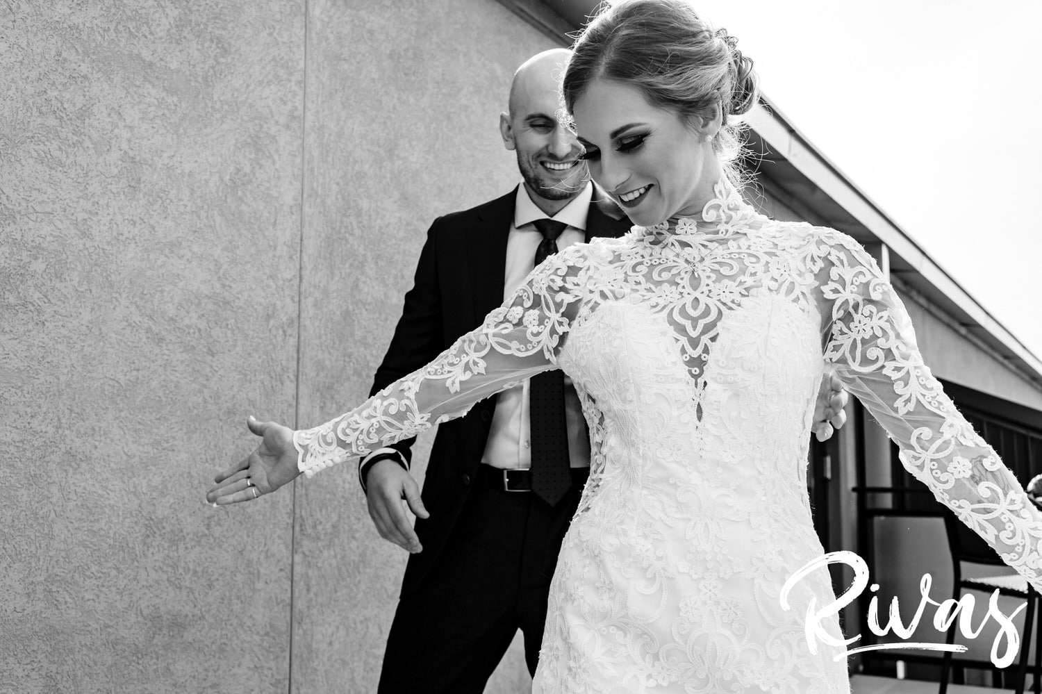 A candid black and white picture of a bride turning in cirlces in front of her groom to show him her gown on the morning of their sunny winter wedding at 28 Event Space. 