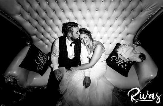 A candid black and white picture of a bride and groom collapsed on a large, tufted sofa during their epic reception at Executive Hills Polo Club.