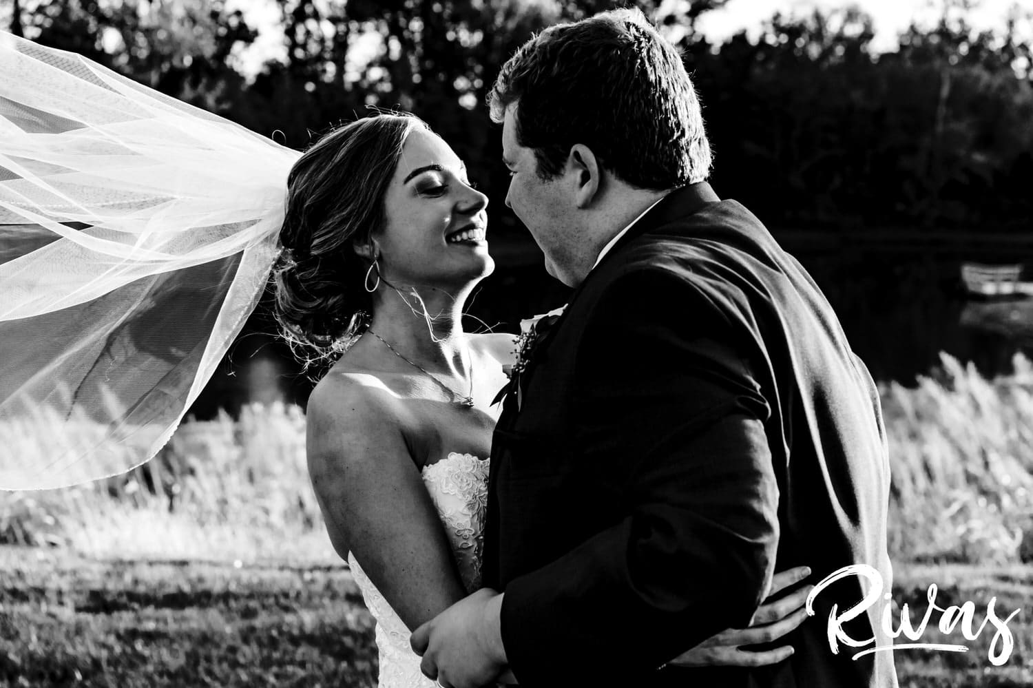 A close-up, candid black and white picture of a bride and groom sharing an embrace and laughing together on the evening of their fall wedding day at Piazza Messina. 