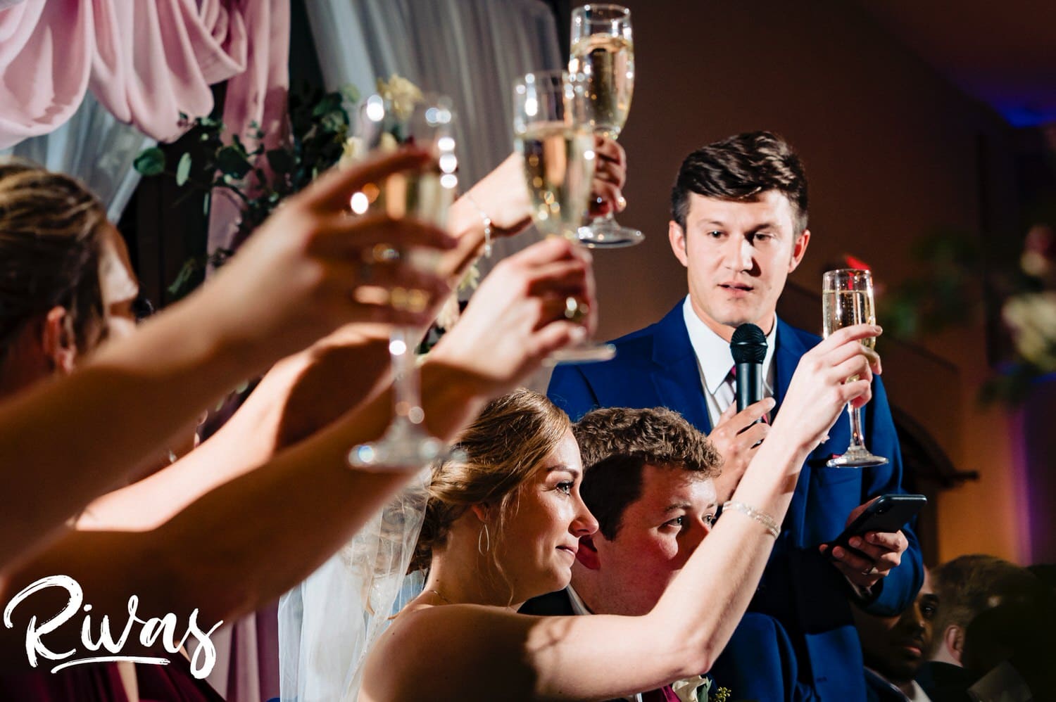 A picture taken through multiple arms lifting champagne glasses in salute as a best man toasts the bride and groom during a wedding reception at Piazza Messina. 