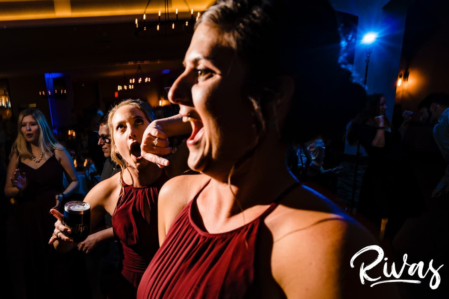 A close-up, candid picture of two bridesmaids excitedly dancing during a fall wedding reception at Piazza Messina. 