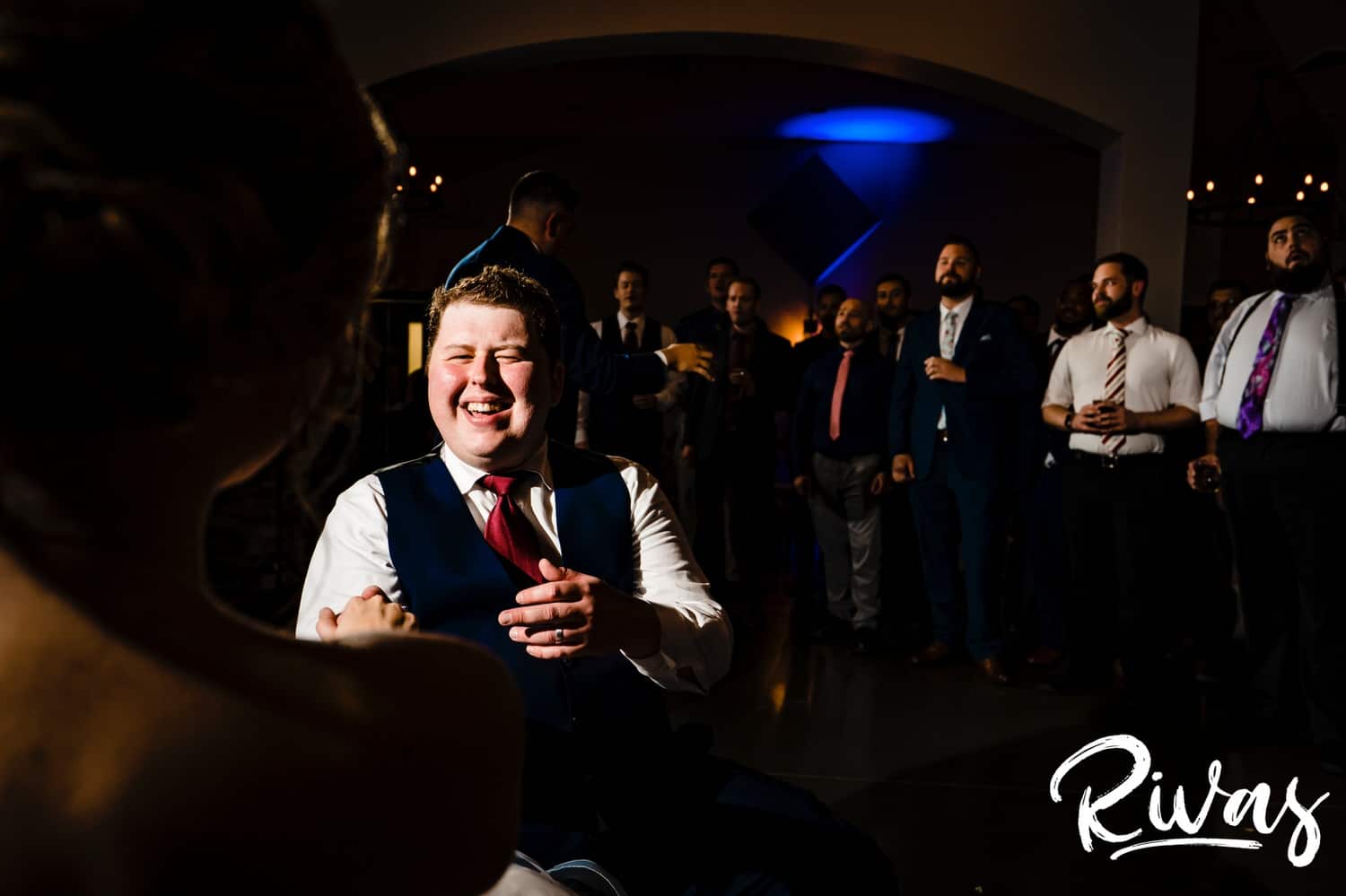A candid picture taken over the shoulder of a bride of her groom, down on one knee, serenading her during their fall wedding reception. 