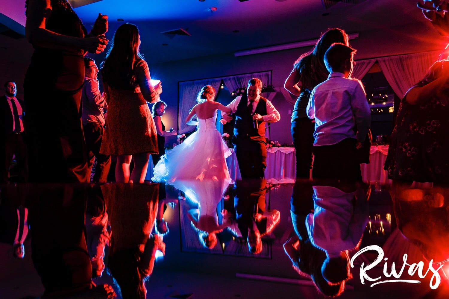 A colorful, candid picture of a bride and groom dancing wildly in the middle of the dance floor during their wedding reception at Piazza Messina. 