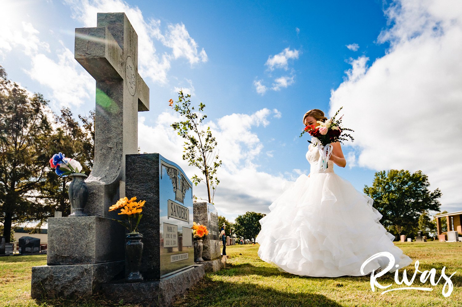 A vibrant image of a bride in a wedding gown walking towards her father's gravestone on her wedding day as the sun breaks through the clouds behind her. 