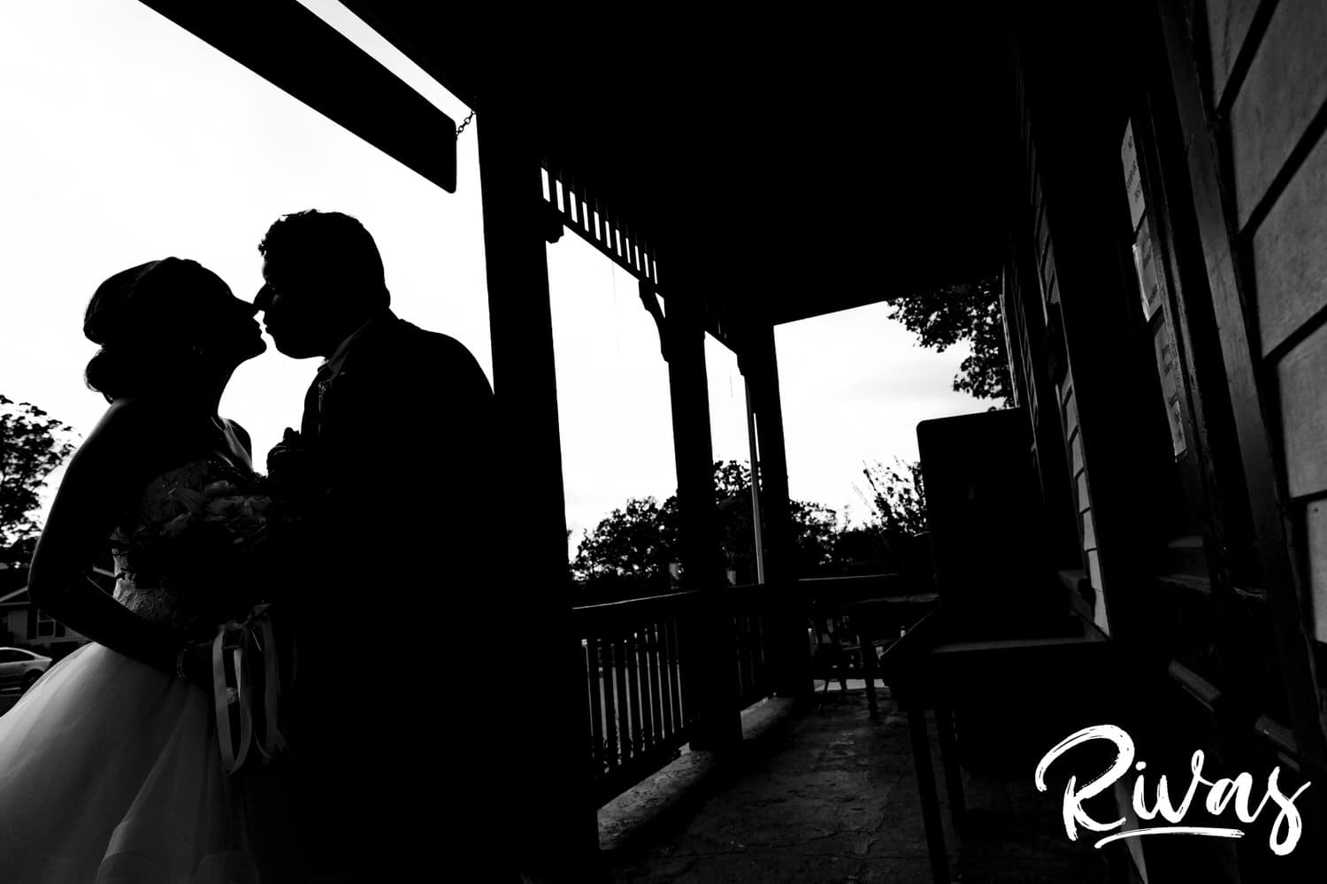 A black and white silhouetted image of a bride and groom learning in to share a kiss in downtown Cottleville, MO on theier fall wedding day. 