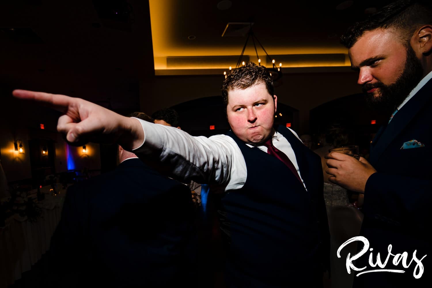 A candid picture of a groom aggressively pointing at someone across the dance floor during his fall wedding reception at Piazza Messina. 