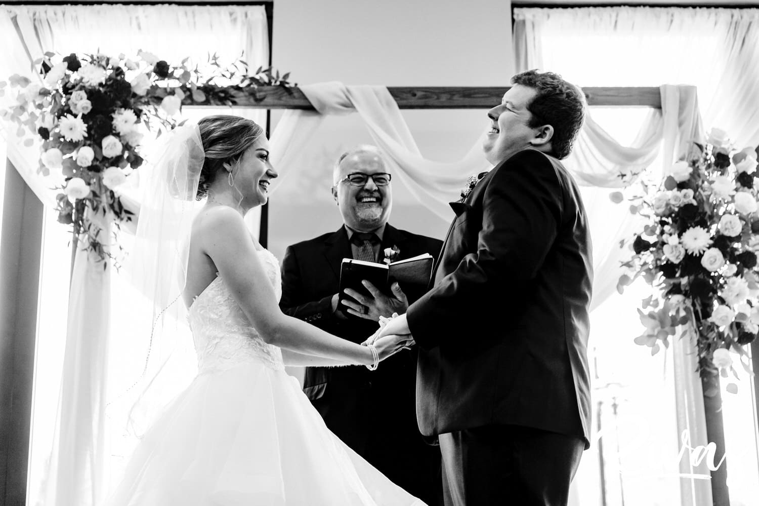 A candid black and white picture of a bride and groom laughing hysterically during their wedding ceremony at Piazza Messina. 