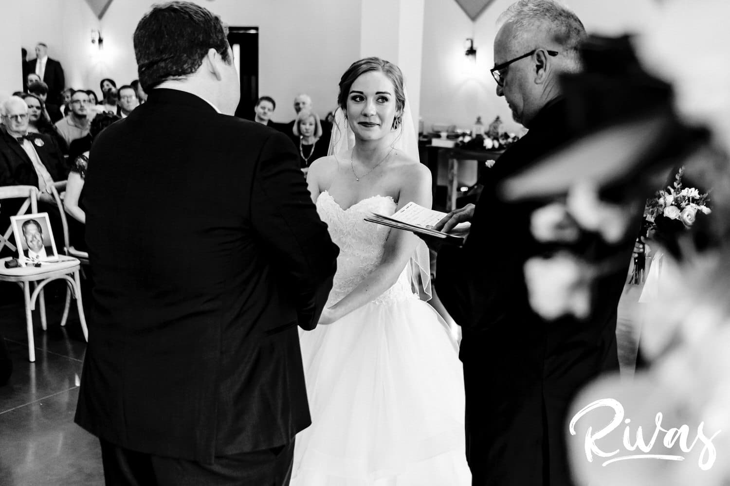 A candid black and white picture taken over the shoulder of the officiant of a bride and groom exchanging their vows during a fall wedding ceremony at Piazza Messina. 