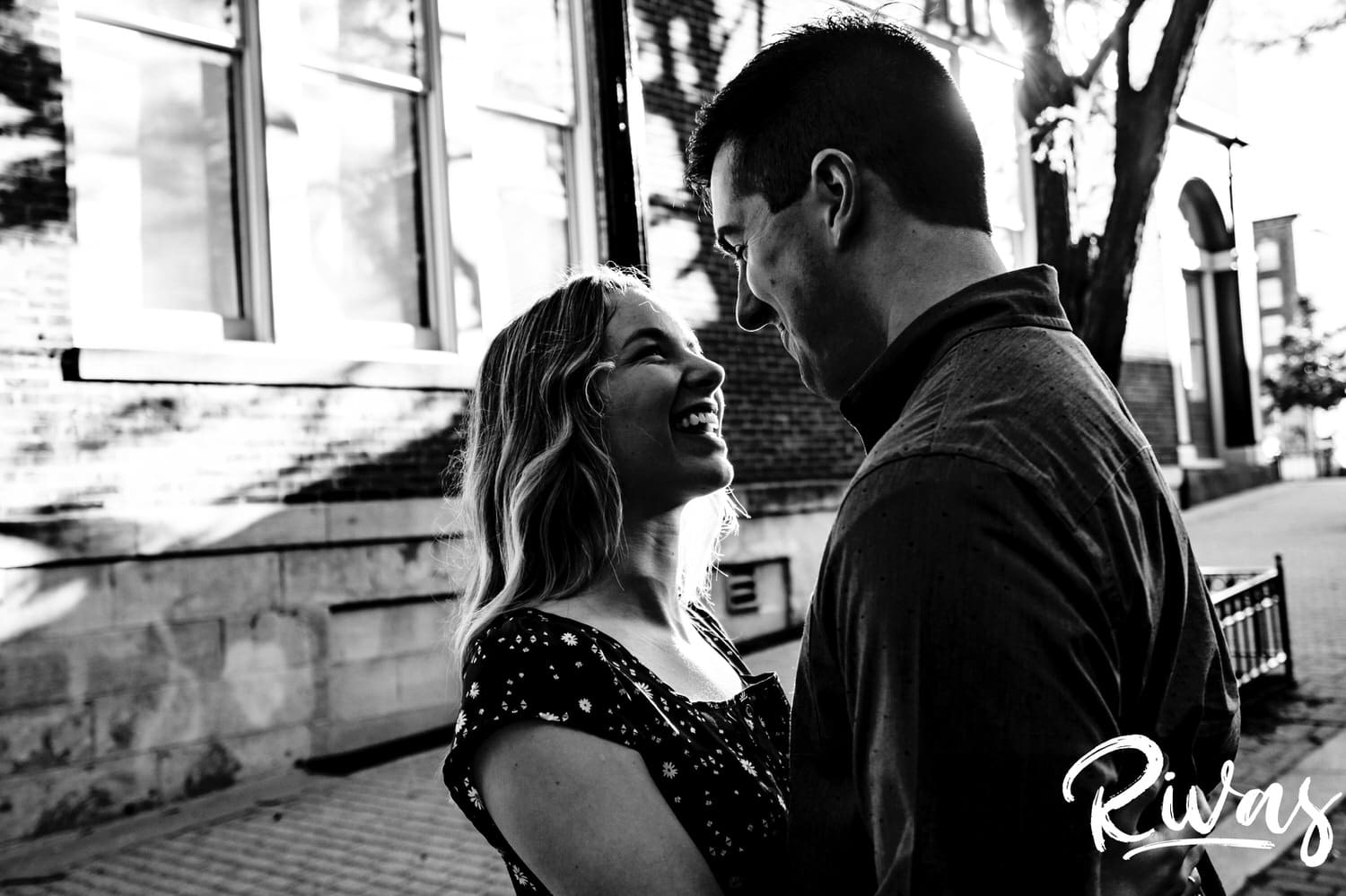 A close-up, intimate black and white picture of an engaged couple sharing an embrace and laughing together during their City Market engagement session. 