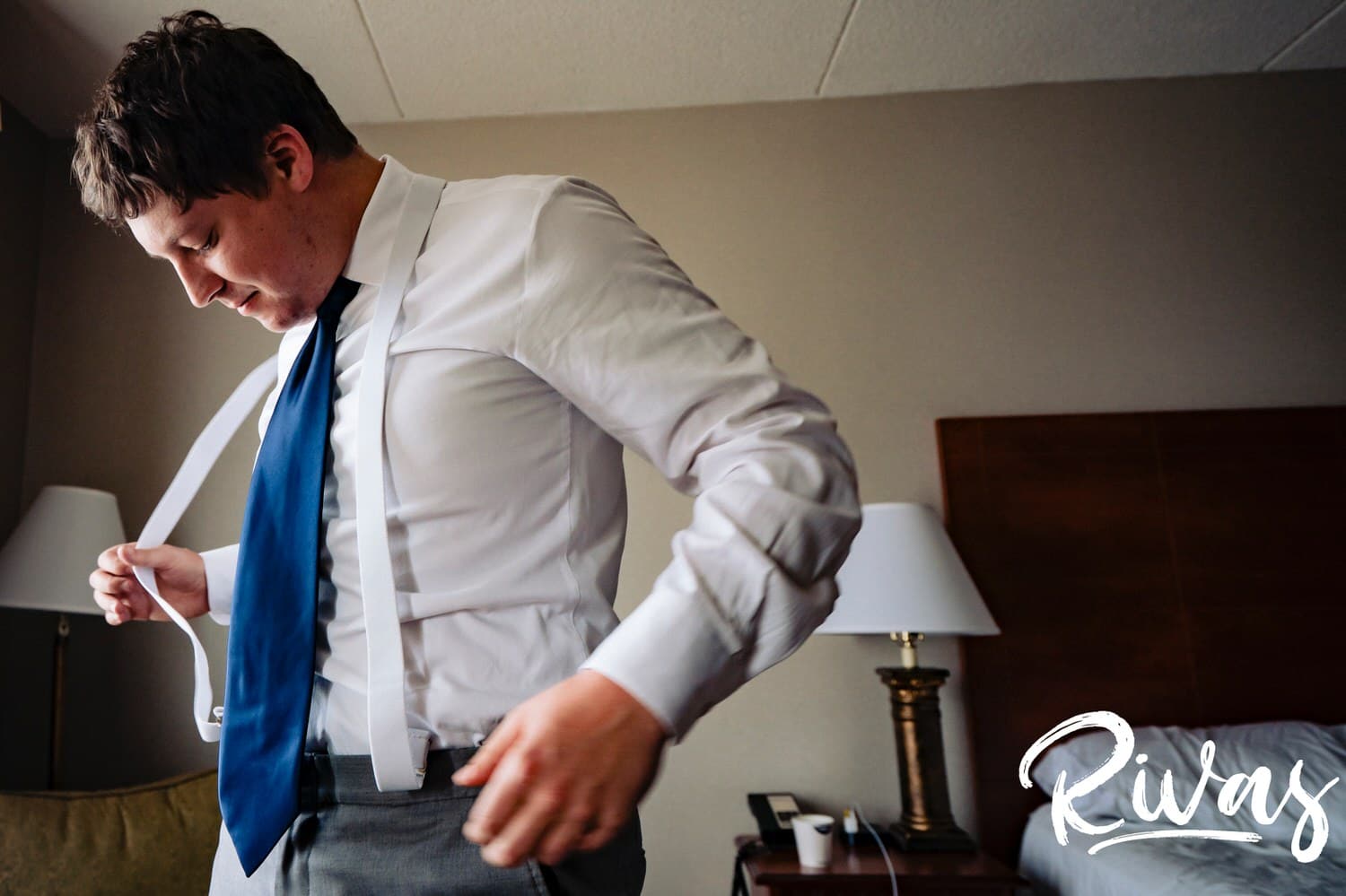 A candid, colorful picture of a groom putting his white suspenders on  as he prepares for his fall wedding at The Barns at Hamilton Station Vineyard. 