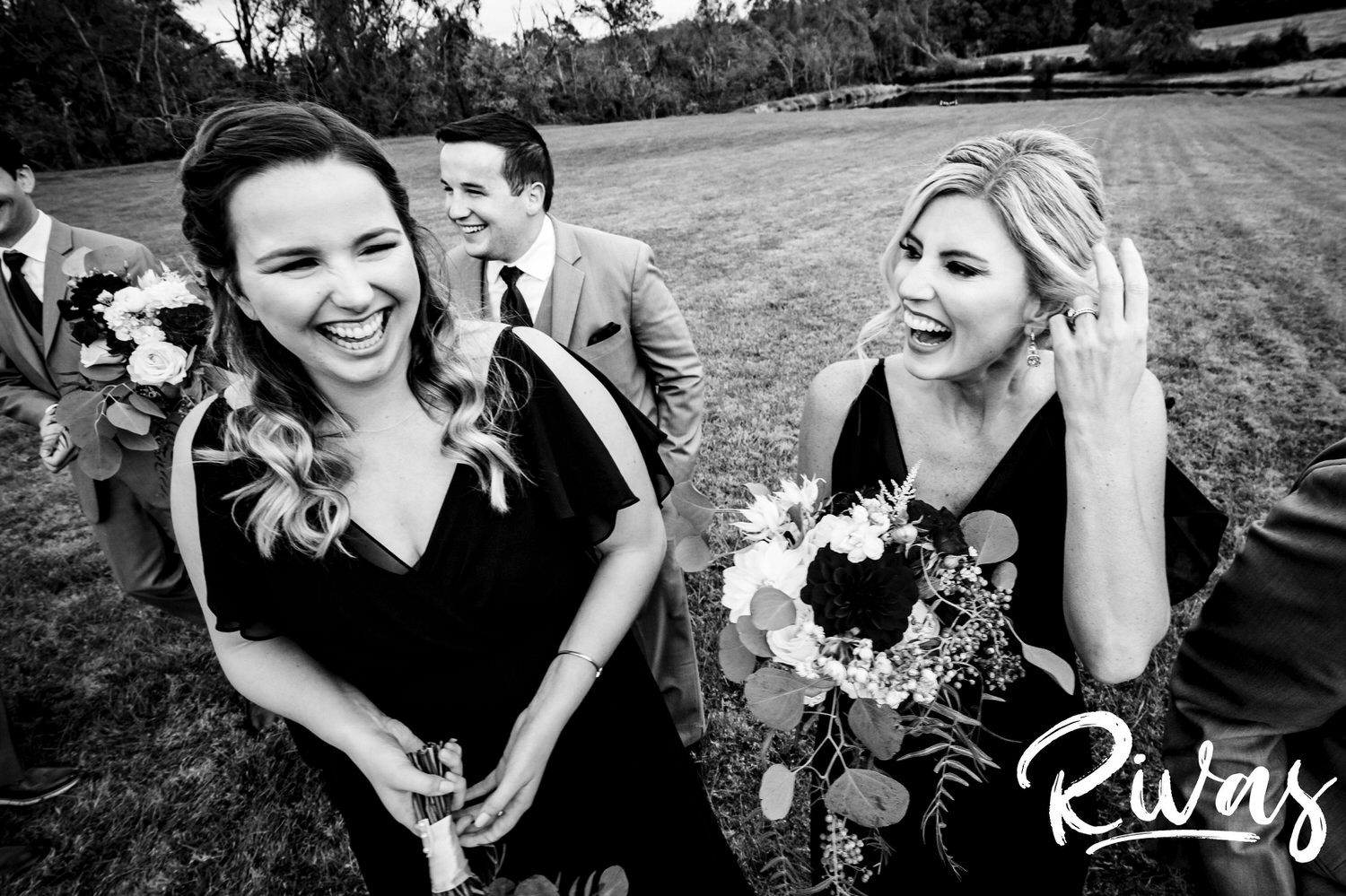 A close-up, candid black and white picture of two bridesmaids and a groomsman laughing hysterically on a fall wedding day. 