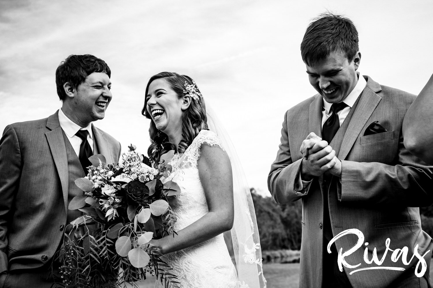 A black and white picture of a bride and groom laughing with their wedding party on the afternoon of their fall wedding day at The Barns at Hamilton Station Vineyard. 
