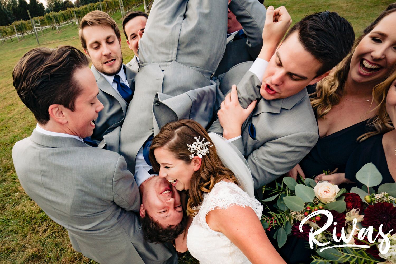 A candid, colorful picture taken from above an upside down groom of his bride and her bridesmaids looking at him laughing on the afternoon of their fall wedding day at The Barns at Hamilton Station Vineyard. 
