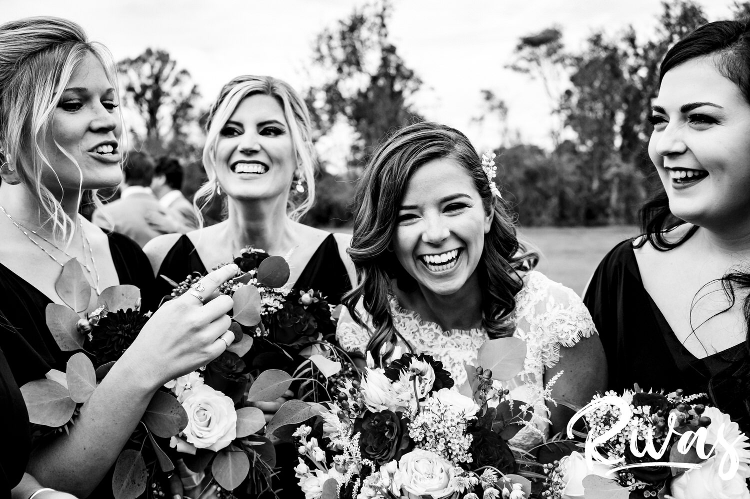 A black and white, candid picture of a bride and her bridesmaids standing together laughing on the afternoon of her fall wedding at The Barns at Hamilton Station Vineyard. 