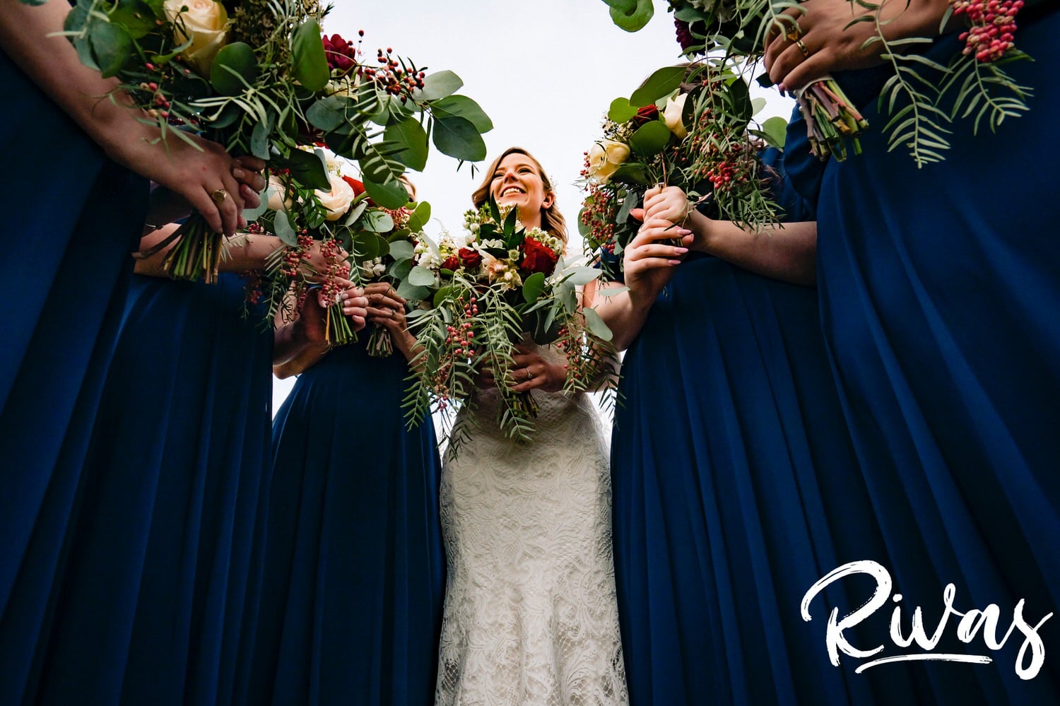 A colorful, candid picture of a bride and her bridesmaids standing together laughing on the afternoon of her fall wedding at The Barns at Hamilton Station Vineyard. 