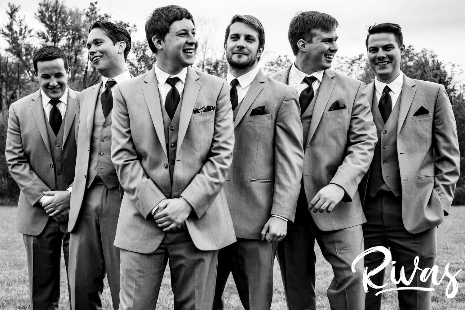 A black and white, candid picture of a groom and his groomsmen standing together laughing on the afternoon of his fall wedding at The Barns at Hamilton Station Vineyard. 
