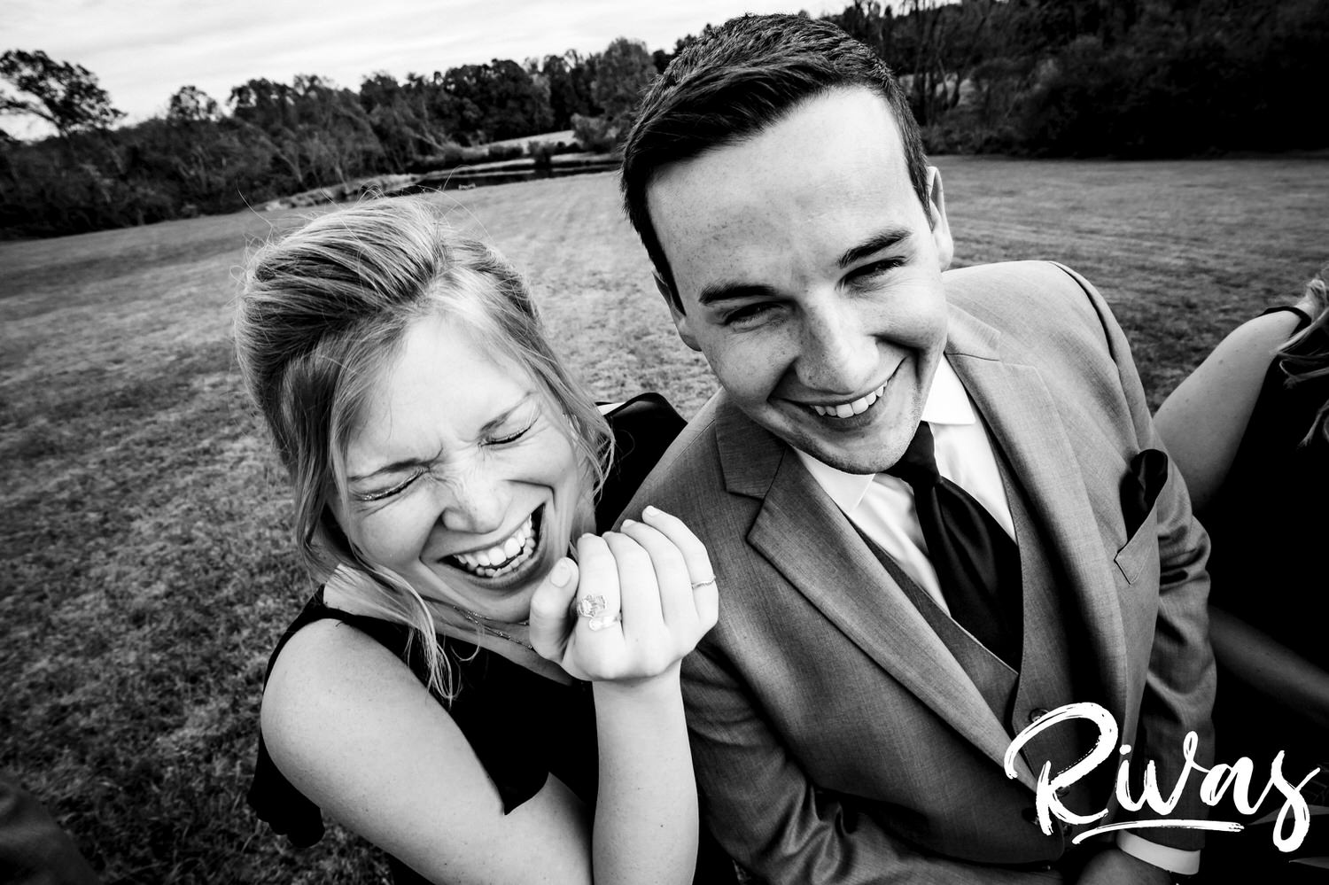 A candid, close-up, black and white picture of a bridesmaid and groomsman laughing hysterically on a fall wedding day.
