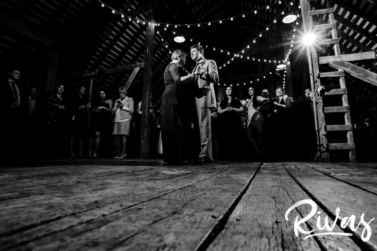 A candid black and white picture of a groom dancing with his mom, taken from the ground up, during his wedding reception at The Barns at Hamilton Station Vineyard. 