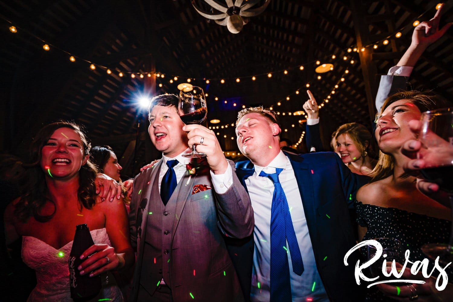 A colorful, candid picture of a bride and groom in the middle of the dance floor surrounded by their family and friends during their fall wedding reception at The Barns at Hamilton Station Vineyard. 