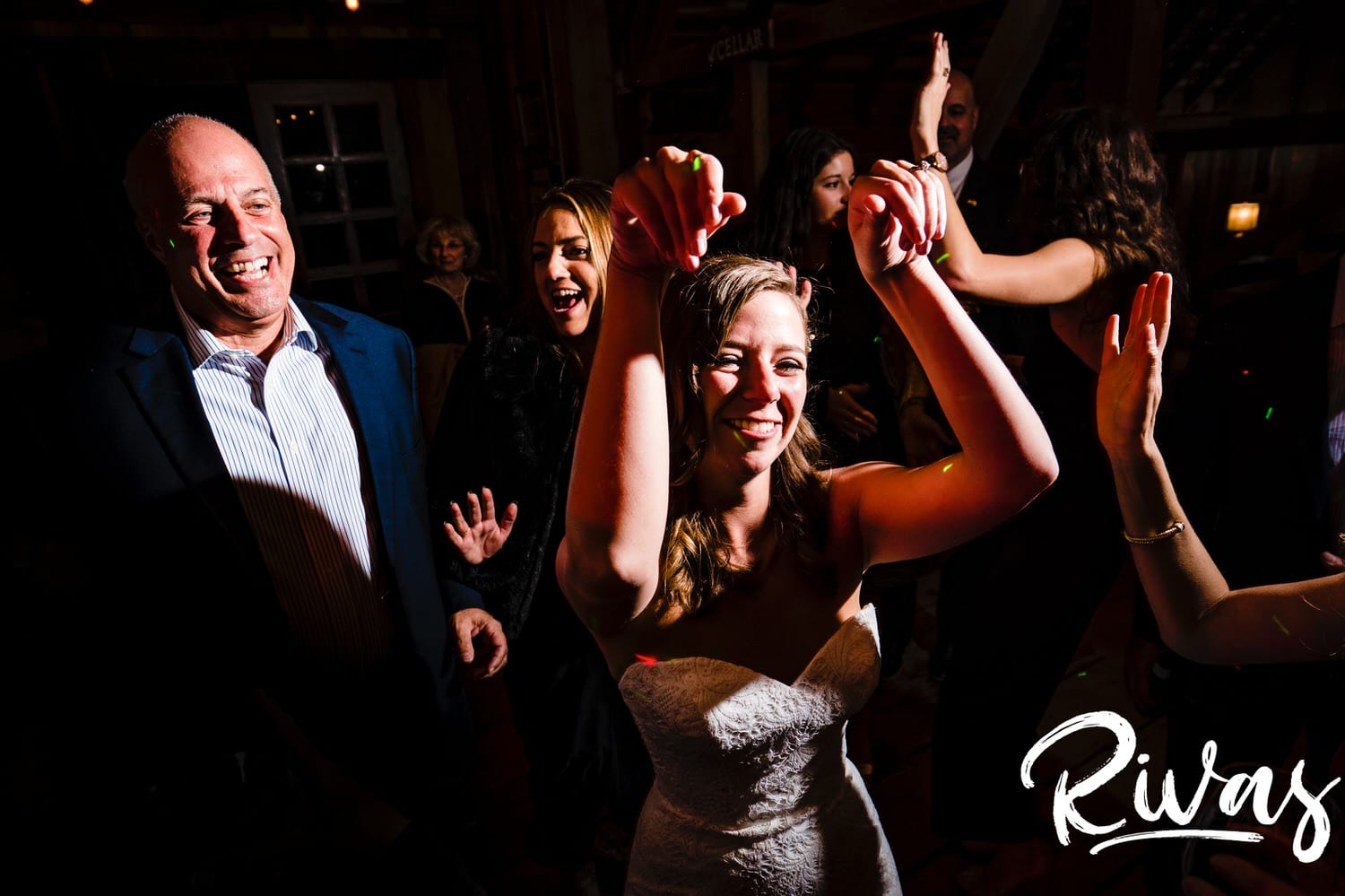A colorful, candid picture of a bride and groom in the middle of the dance floor surrounded by their family and friends during their fall wedding reception at The Barns at Hamilton Station Vineyard. 