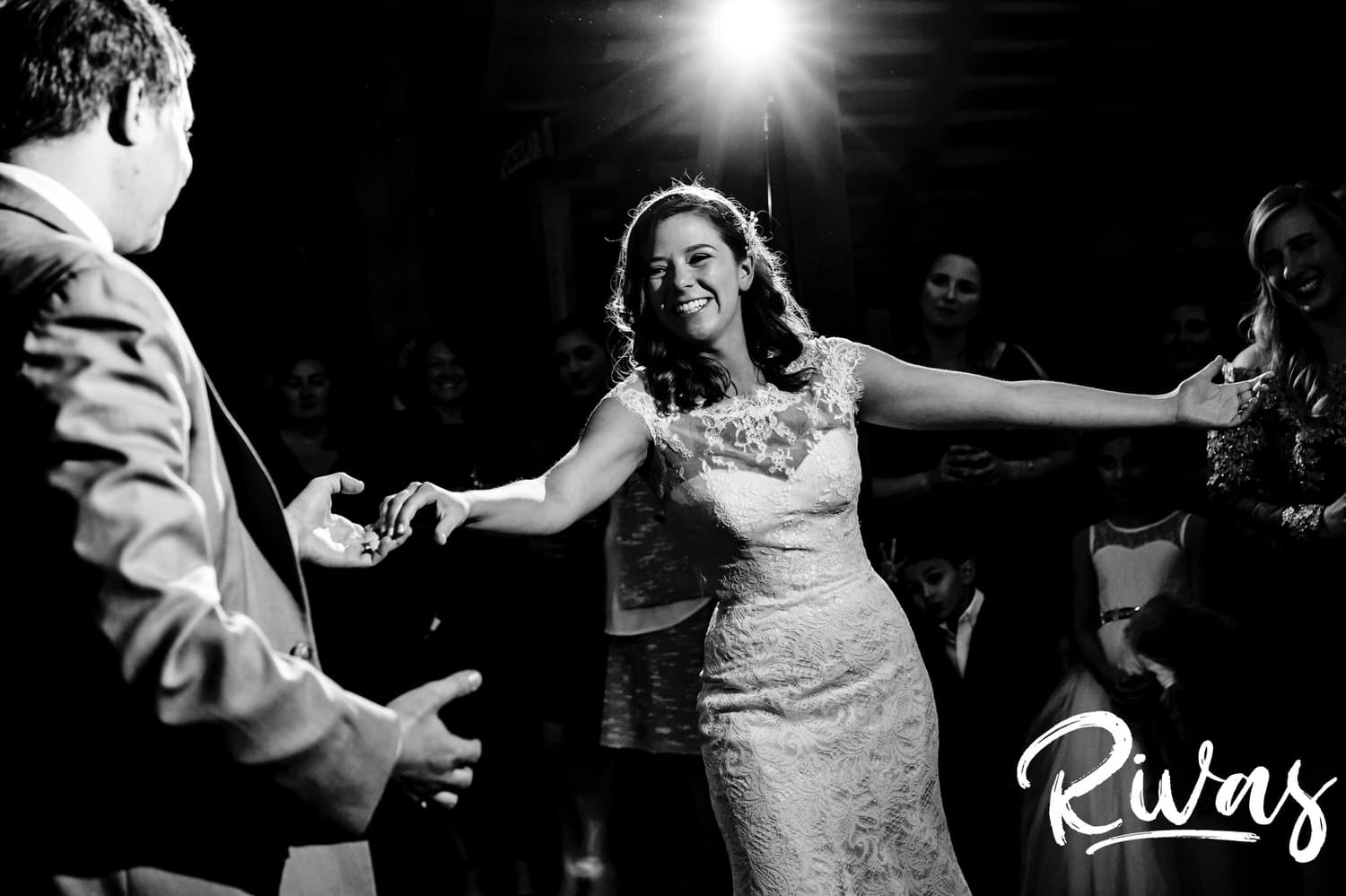 A candid black and white picture of a groom showing his bride off at the end of their first dance during their fall wedding reception at The Barns at Hamilton Station Vineyard. 
