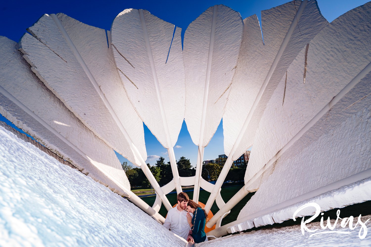 A colorful portrait of an engaged couple at the center of a shuttlecock on The Nelson's lawn during their engagement session in Kansas City. 