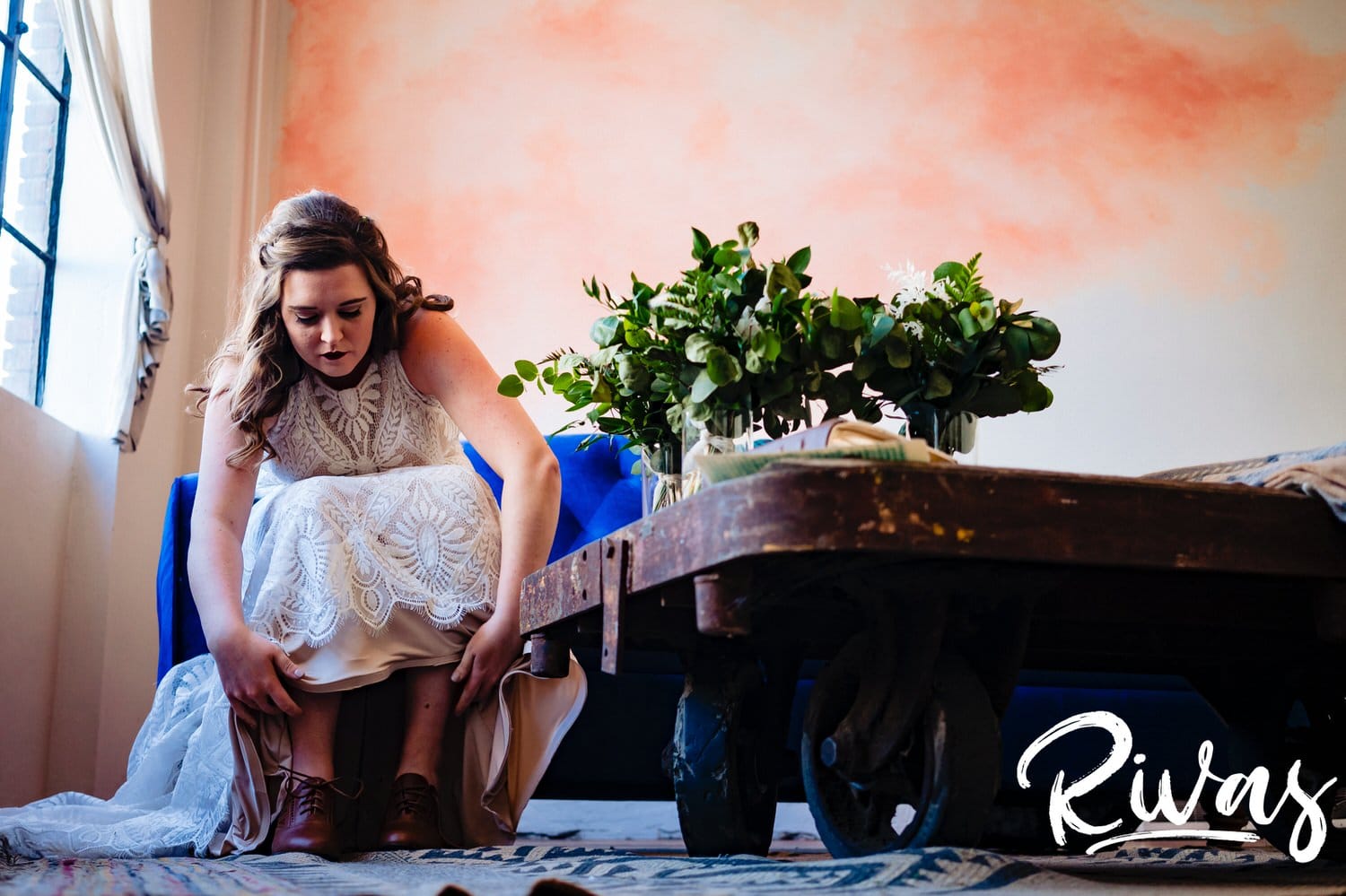 A colorful, candid picture taken from the floor of a bride leaning over to tie her shoes on the afternoon of her fall wedding day in Kansas City. 