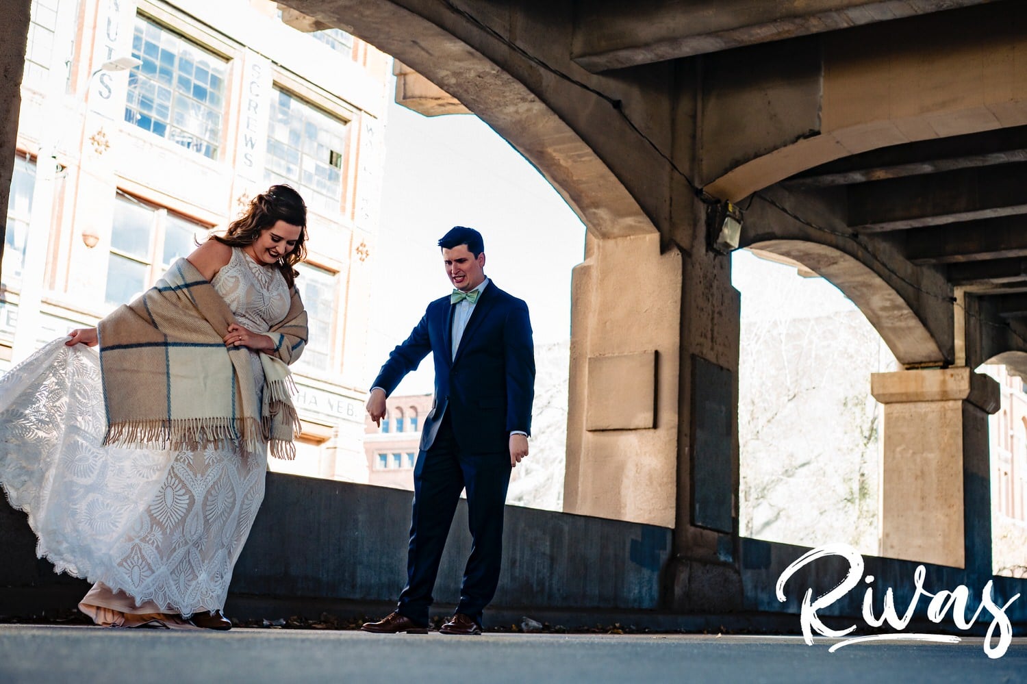 A colorful, candid picture of a groom instructing his bride to twirl around so he can see her full gown during their first look on a fall wedding day in Kansas City. 