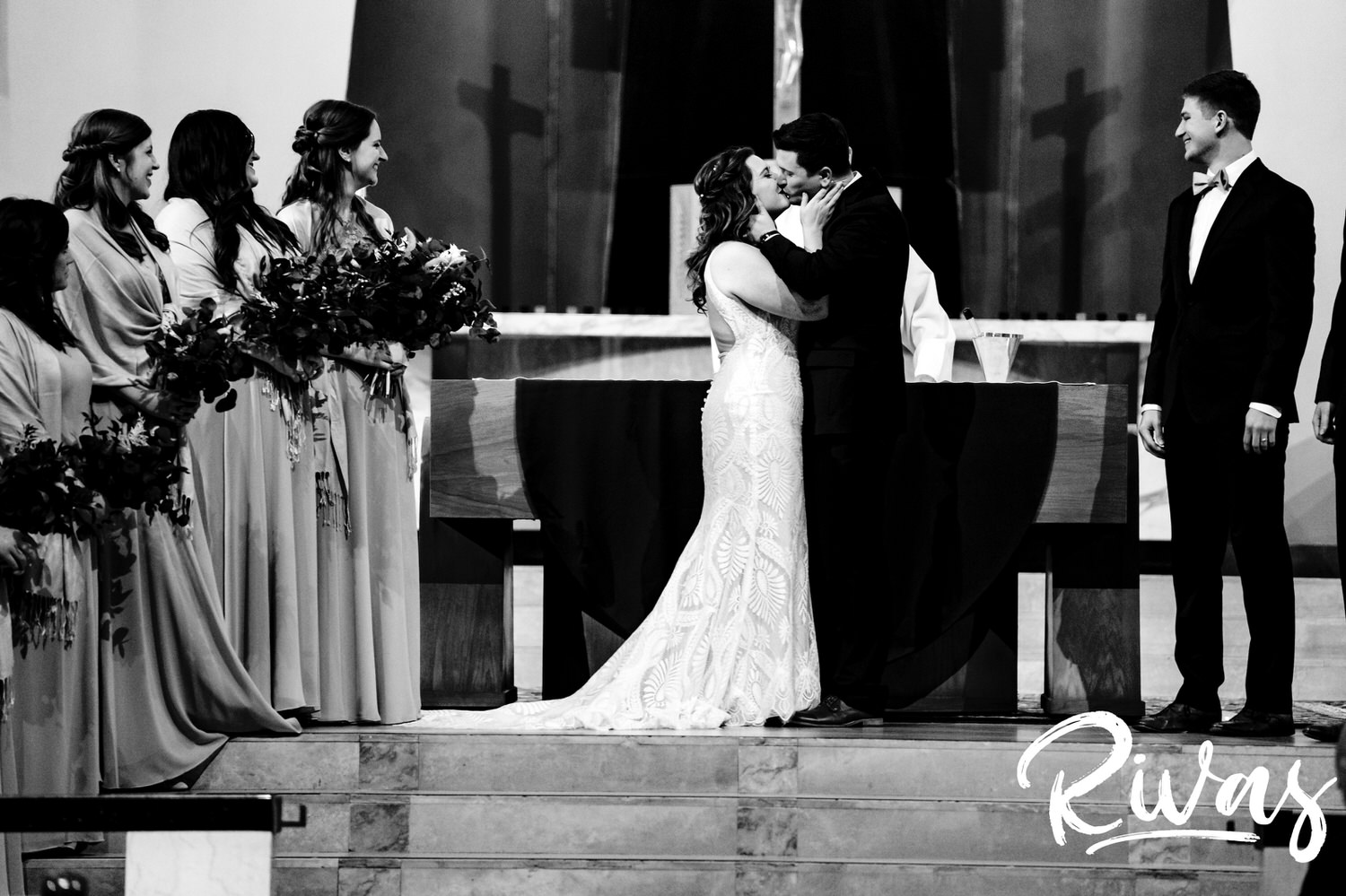 A candid black and white picture of a bride and groom sharing their first kiss during their wedding ceremony. 