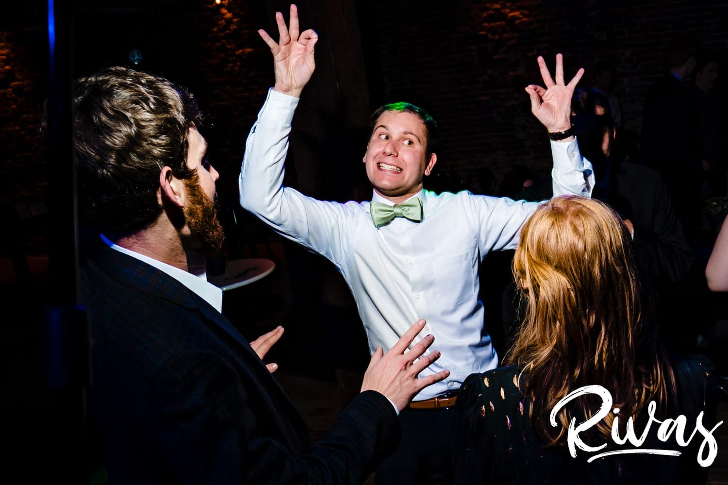 A colorful, candid picture of a bride and groom dancing together with their guests during their wedding reception at The Foundation Event Space in Kansas City. 